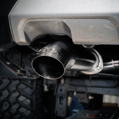 Close-up of a car exhaust system with a focus on the muffler and tailpipe.